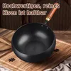 A black wok with a wooden handle rests on a wooden cutting board, with some spices scattered around. The background is a woven texture. Produktbild-Vorschau