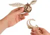Hands holding a wooden model of the Golden Snitch from Harry Potter and a stand for it. Náhled obrázku produktu
