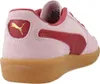 A close-up, rear-side view of a pink Puma sneaker with red accents and a gum sole. Produktbild-Vorschau