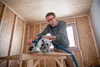 A man is using a circular saw in a room under construction. Podgląd zdjęcia produktu