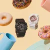 Two Casio Baby-G watches are displayed with donuts and mugs. Anteprima dell’immagine prodotto