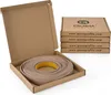 A roll of beige edge banding tape is shown in an open cardboard box, with a stack of identical boxes in the background. Náhľad obrázku produktu