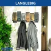 A wall-mounted coat rack with five wooden panels, each with a hook, and two jackets hanging on it. A large green plant is to the left. Produktbild-Vorschau