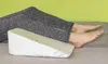 A person's legs are resting on a wedge pillow. Náhled obrázku produktu