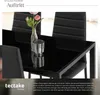 A close-up view of a modern black dining table with chairs, a vase with flowers, and a decorative glass object. Náhled obrázku produktu