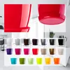A collage of various colored plastic plant pots with saucers, displayed in rows against a light background. The top section shows close-ups of red pots. Anteprima dell’immagine prodotto
