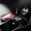A car's center console with multiple phones and a car charger plugged in. Podgląd zdjęcia produktu