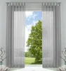 A view through a window with sheer gray curtains, showing a green tree and blue sky. Produktbild-Vorschau