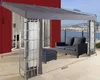 An outdoor canopy with furniture on a patio overlooking a body of water and a city. Produktbild-Vorschau