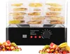 A food dehydrator with multiple trays filled with dried fruit, placed on a surface with a pile of fresh fruit in the foreground. Produktbild-Vorschau