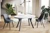 A dining table and chairs set up in a modern living space with plants and a spiral staircase. Voir les images du produit