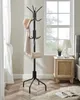 A coat rack with a hat and bag on it, next to a nightstand with a lamp and plant, in a room with a window. Náhled obrázku produktu
