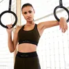 A woman is posing with gymnastic rings in a gym. Produktbild-Vorschau