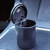 A black car ashtray with its lid open, sitting on a textured surface inside a car. Náhled obrázku produktu