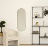 A mirror is shown in a room setting next to a chair and a shelf unit. Anteprima dell’immagine prodotto