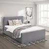 A bedroom scene featuring a grey upholstered bed with storage drawers, bedside tables, lamps, and artwork on the wall. Produktbild-Vorschau