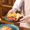 A person is holding a plate of fruit and another plate with pasta. Náhled obrázku produktu