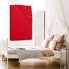 A red fitted sheet is displayed prominently on a white bed frame, with other bedding and bedroom furniture in the background. Produktbild-Vorschau