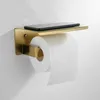 A close-up of a gold toilet paper holder mounted on a white wall, with a roll of toilet paper and a smartphone on the shelf. Anteprima dell’immagine prodotto