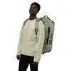 A man wearing a beige sweater and black pants is modeling a green duffel bag/backpack. Produktbild-Vorschau