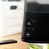 Close-up of a black humidifier with a digital display and a remote control on a wooden surface. Podgląd zdjęcia produktu