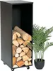 A black metal firewood rack filled with logs, next to a potted green plant. Produktbild-Vorschau