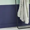 A close-up shot of a beige fabric draped over a black metal stand against a wall painted in two tones of light green and dark blue. Anteprima dell’immagine prodotto
