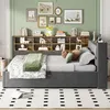 A bedroom scene featuring a daybed with a bookshelf headboard, decorated with artwork and accessories. Produktbild-Vorschau
