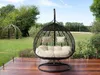 A hanging egg chair with cushions is placed on a wooden deck in a garden setting. Náhled obrázku produktu