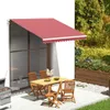 An outdoor patio scene with a table and chairs set up under a burgundy awning, with a grill to the side and a planter box in the background. Náhled obrázku produktu
