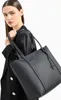 A woman is holding a black tote bag. Podgląd zdjęcia produktu