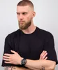A man wearing a black t-shirt and a watch on his left wrist, with his arms crossed. Voir les images du produit