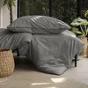 A bed with gray and black striped bedding is shown in a room with plants and natural light. Produktbild-Vorschau