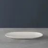 A white oval plate on a gray surface against a dark blue background. Podgląd zdjęcia produktu