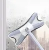 A window cleaning tool is being used to clean a window with water droplets on it. The background shows a blurred cityscape. Produktbild-Vorschau