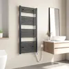 A modern bathroom with a dark grey electric towel warmer mounted on the wall next to a vanity with a sink and mirror. Voir les images du produit