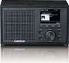 A black Lenco digital radio is shown from the front, with its screen displaying station information and song details. The radio is placed on a reflective surface, creating a mirror image below it. Produktbild-Vorschau