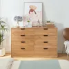 A wooden dresser with eight drawers is shown in a bedroom setting, with a plant and artwork on top. Produktbild-Vorschau