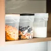 Three clear plastic storage containers with lids are lined up on a shelf. The containers hold different food items: cereal, nuts and dried fruit, and a white powder. Produktbild-Vorschau
