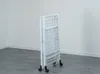 A white folding drying rack with wheels is shown standing upright in a room with a light gray floor and white walls. Produktbild-Vorschau