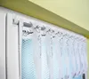 Close-up of a white lace curtain hanging on a curtain rod in front of a window. Produktbild-Vorschau