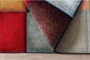 A close-up view of a colorful, patterned rug with a section folded back to reveal the underside. Produktbild-Vorschau