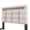 A close-up view of a beige upholstered headboard with a tufted design, attached to a black metal bed frame. Produktbild-Vorschau