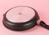 The underside of a frying pan is shown against a pink background. Náhľad obrázku produktu