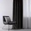 A dark gray velvet curtain is shown next to a sheer white curtain, with a dark gray accent chair and a gray pillow in the foreground. Produktbild-Vorschau