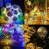 A collage of four images showing decorative string lights with spherical, perforated globes, illuminated with warm white light and casting patterned shadows. Produktbild-Vorschau