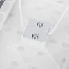 A close-up view of the underside of a white ironing board, showing a metal plate with two screws attaching a white plastic component. Produktbild-Vorschau