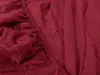A close-up view of a rumpled burgundy bed sheet with elastic gathering. Produktbild-Vorschau