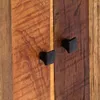 A close-up view of two black knobs on a wooden cabinet. Náhled obrázku produktu