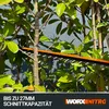 Close-up of a hedge trimmer blade cutting through branches of a green leafy bush. Produktbild-Vorschau